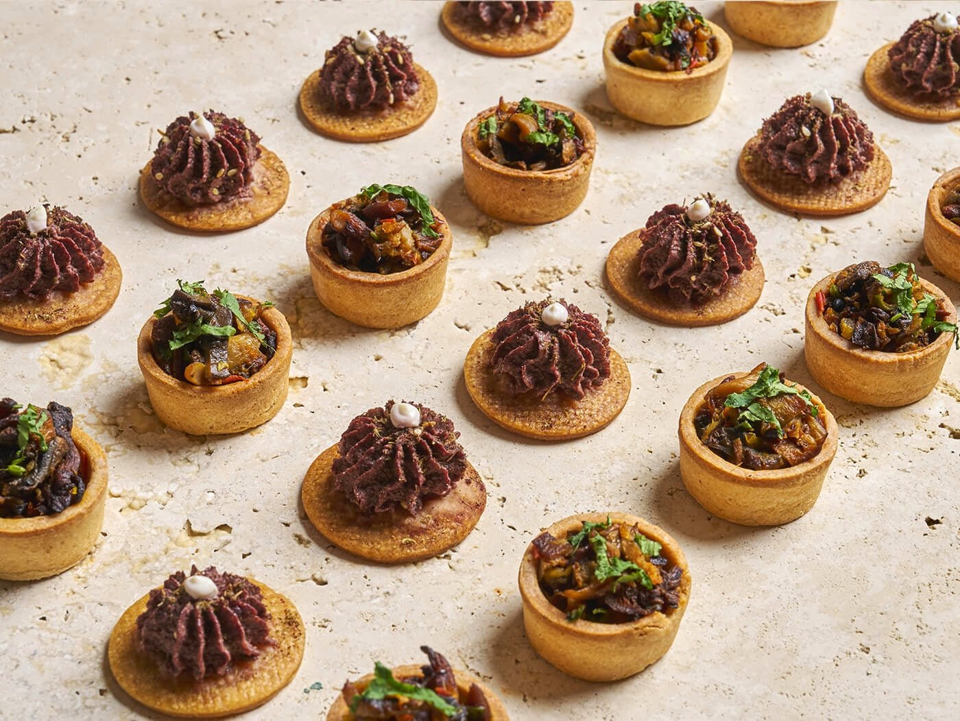 Assortiment de pièces salées : Crackers à l'olive noire et za'atar, Tartelettes aux champignons et baies de Timut - Les Cuistots Migrateurs